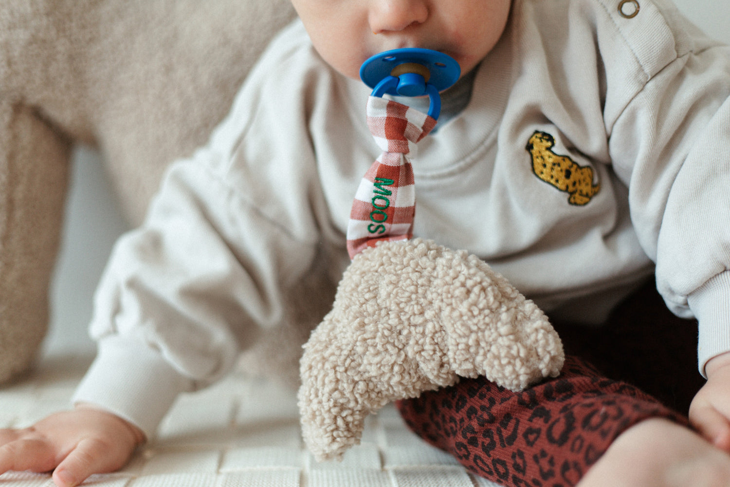 speenkoord met een rood geruit patroon met daaraan een teddy croissant