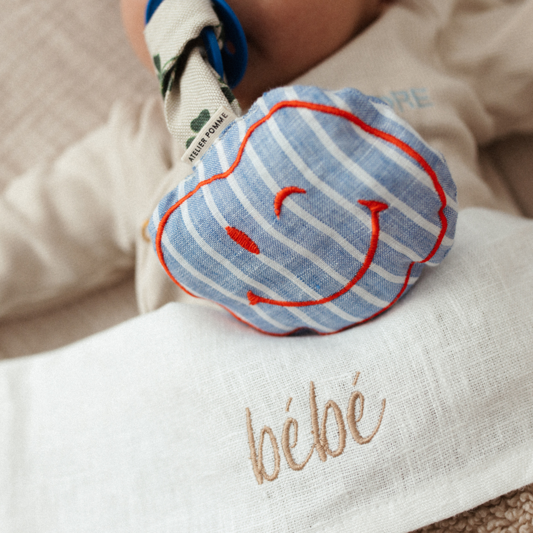 Blauw-wit gestreept linnen speenkoord met een rode smiley, geschikt voor baby&