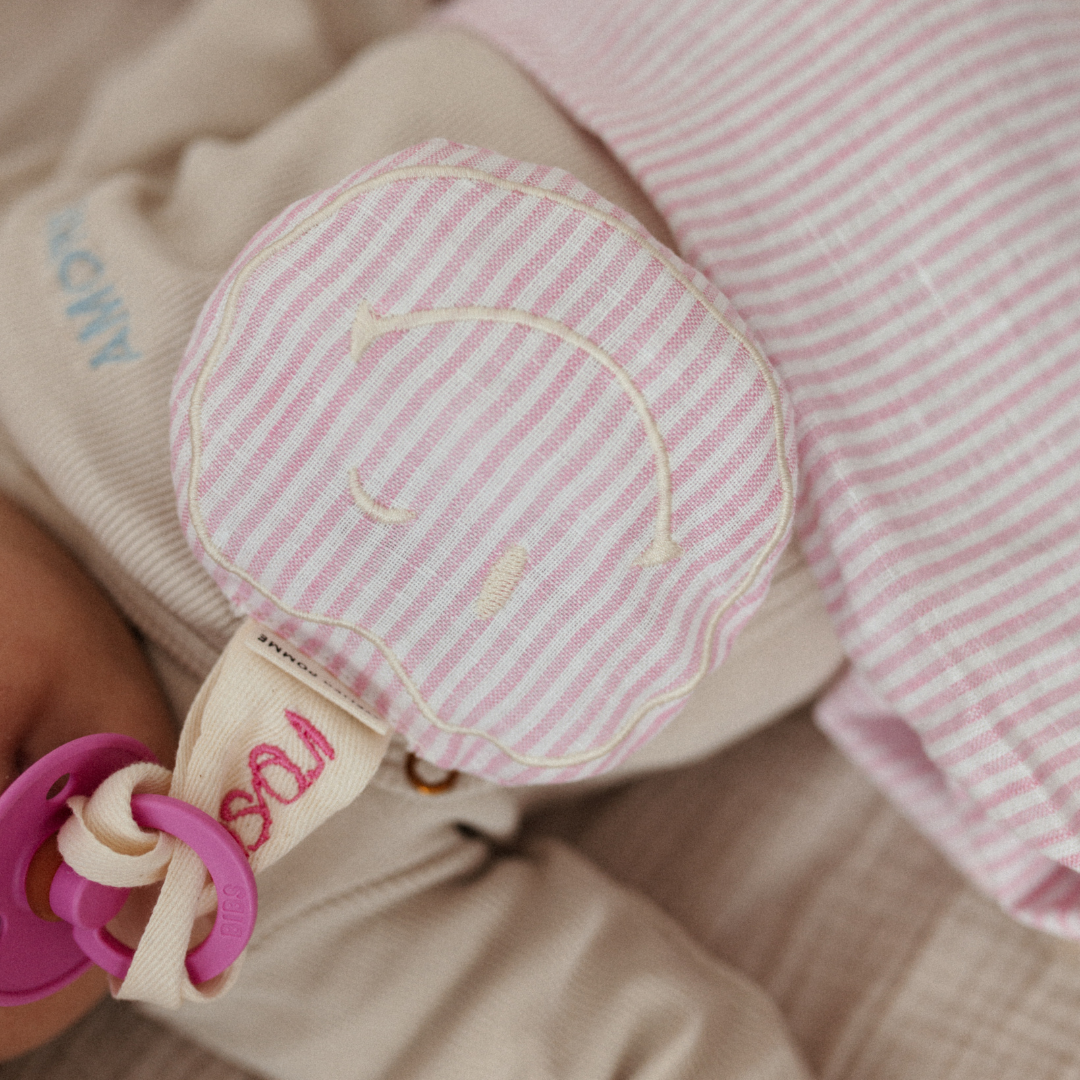 Roze met wit linnen speenkoord met een witte smiley knuffel, leuk als geboorte cadeau.