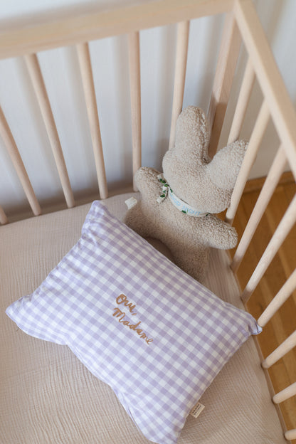 Een lila geruit kussen met een gepersonaliseerde tekst erop