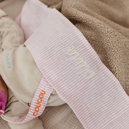 baby ligt onder laken met gepersonaliseerde tekst en speenkoord