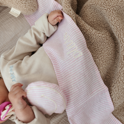 baby ligt onder laken met tekst, speen en speenkoord