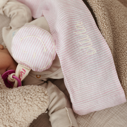baby ligt onder laken met tekst. knuffel, speen, gestreept speenkoord met tekst. 