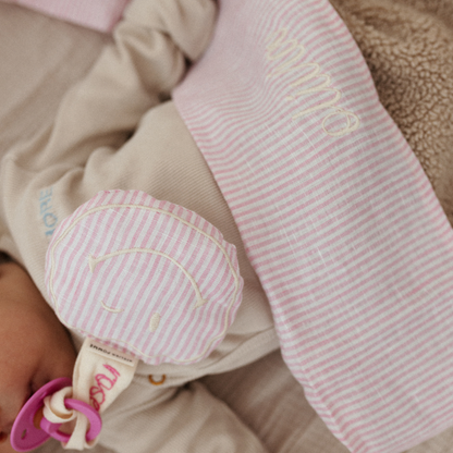 baby ligt onder laken met tekst. speen, gestreept speenkoord met tekst. 