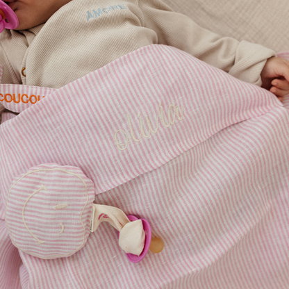 baby ligt onder laken met tekst. speen met speenkoord