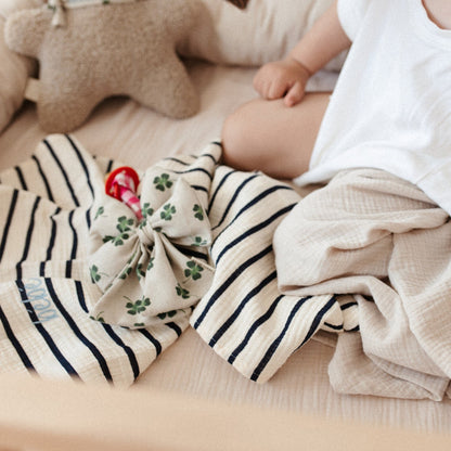 zittende baby, lakens, knuffel, speen met speenknuffel