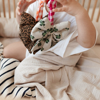 zittende baby met spenen in de mond met daaraan speenknuffels. lakens en knuffel