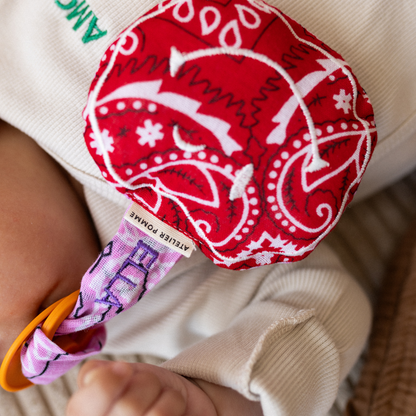 baby met speen in de mond met daaraan een speendoekje met tekst. 