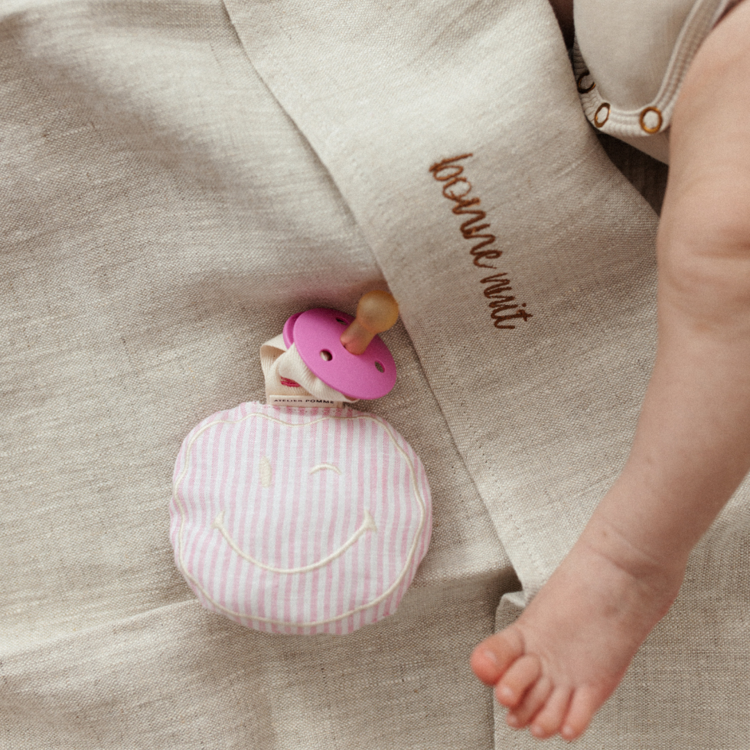 Roze-wit linnen speenkoord met een schattige witte smiley knuffel