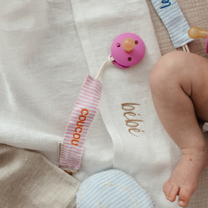 baby ligt op laken met tekst, speen met speenkoorden met tekst