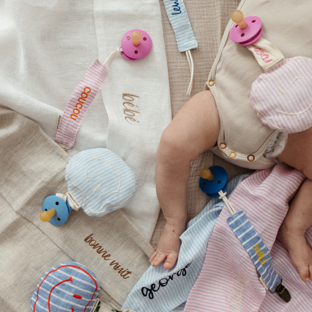 baby ligt op laken met tekst, spenen met speenknuffels en speenkoorden met tekst