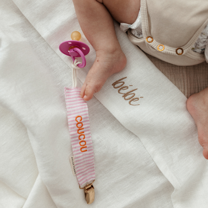 baby ligt op laken, speen en speenkoord met tekst 