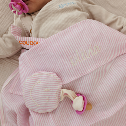 baby ligt onder laken met tekst, spenen met speenknuffel en speenkoord met tekst