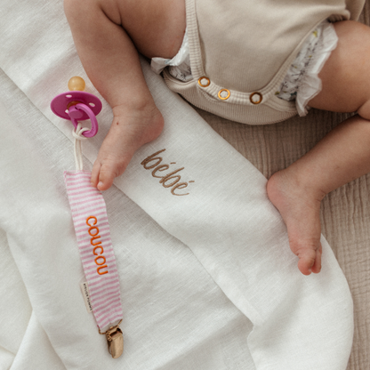 baby ligt op laken met tekst, speen met speenkoord met tekst