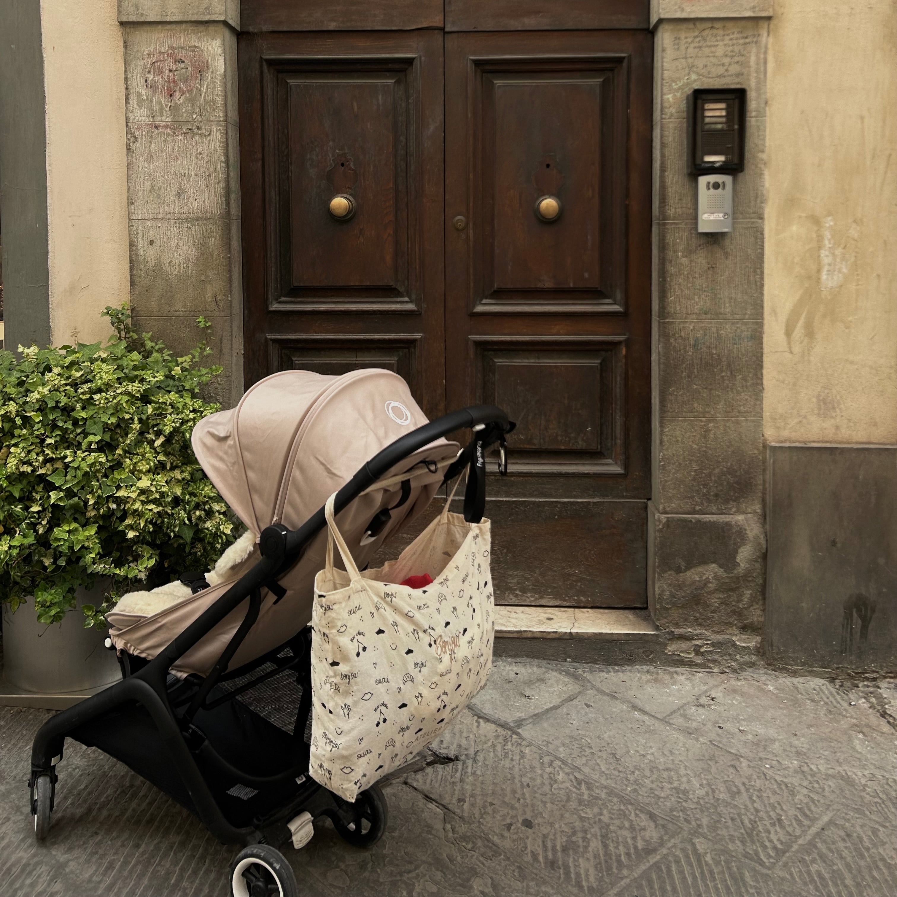 canvas tas met print hangt over het handvat van een kinderwagen. 