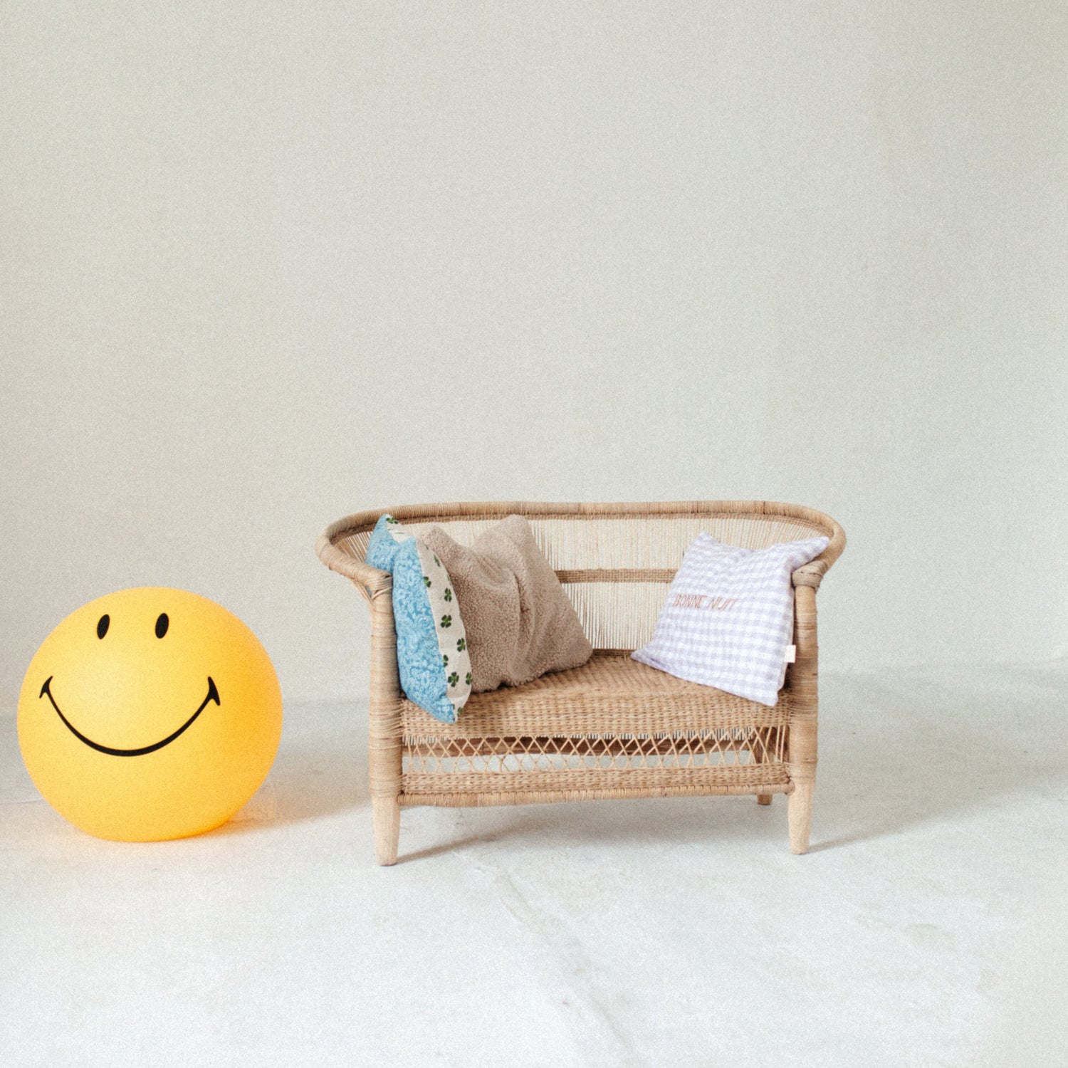 smiley lamp op staat op de grond naast stoel met kussens