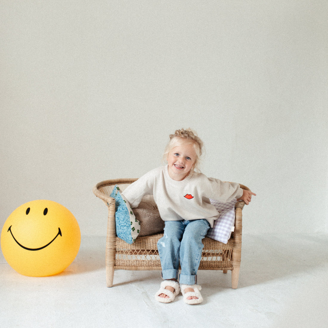 smiley lamp staat op de grond naast stoel waar een kind op zit