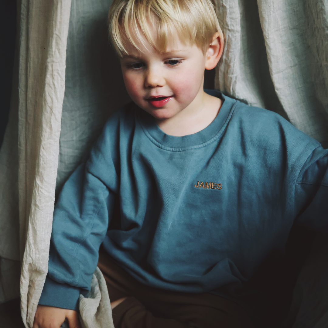 kind draagt een blauwe sweater met gepersonaliseerde tekst 