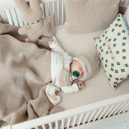 baby ligt onder teddy deken. kussen met tekst en teddy knuffel