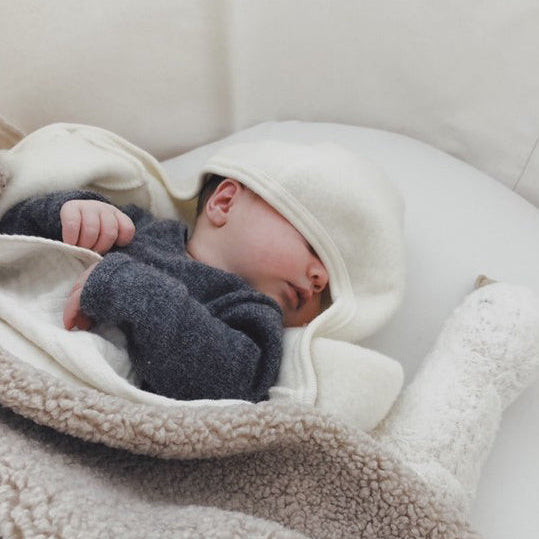 baby ligt onder teddy deken met vogel. 