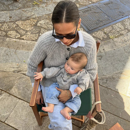baby met grijze sweater zit bij vrouw op schoot