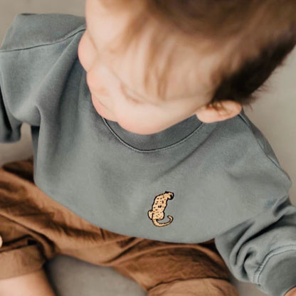 baby draagt blauwe sweater met icoon. 