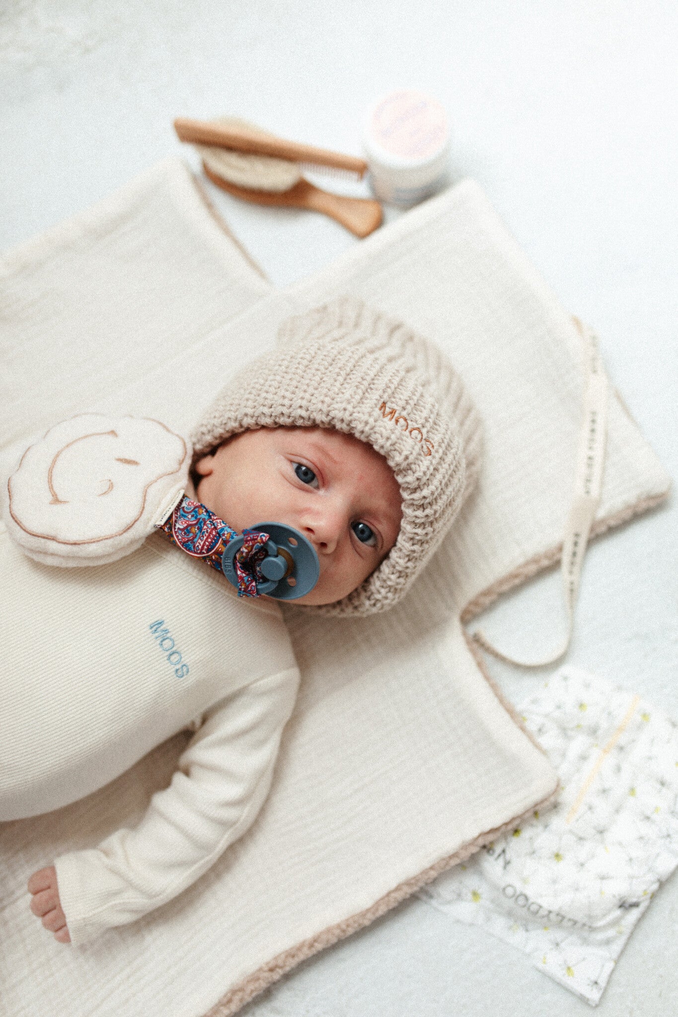 baby met een wollen speen knuffel in de vorm van een smiley