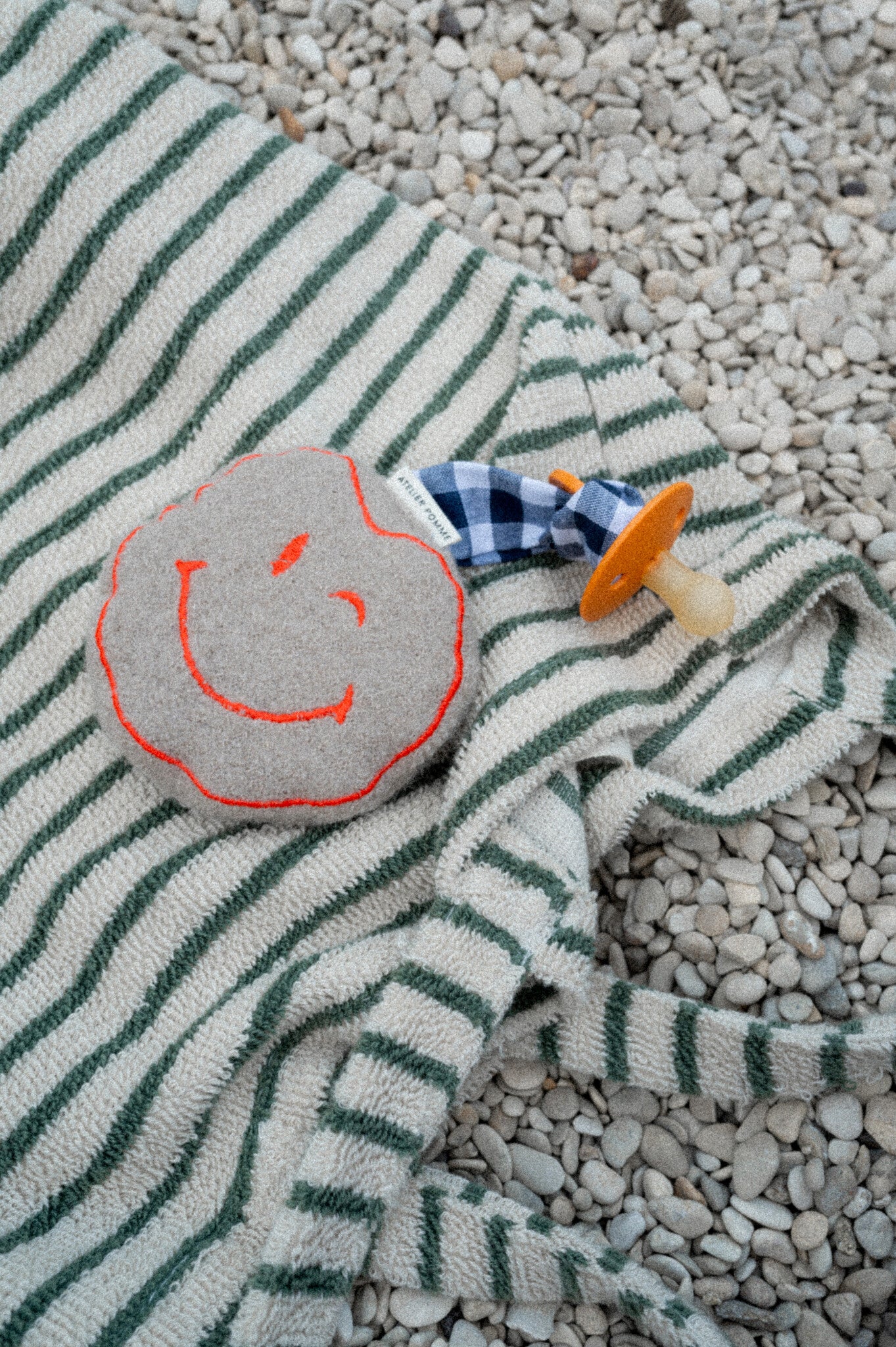 Smiley knuffel speenkoord van zachte wollen stof met een oranje smiley, met een koord om een speen aan te bevestigen.