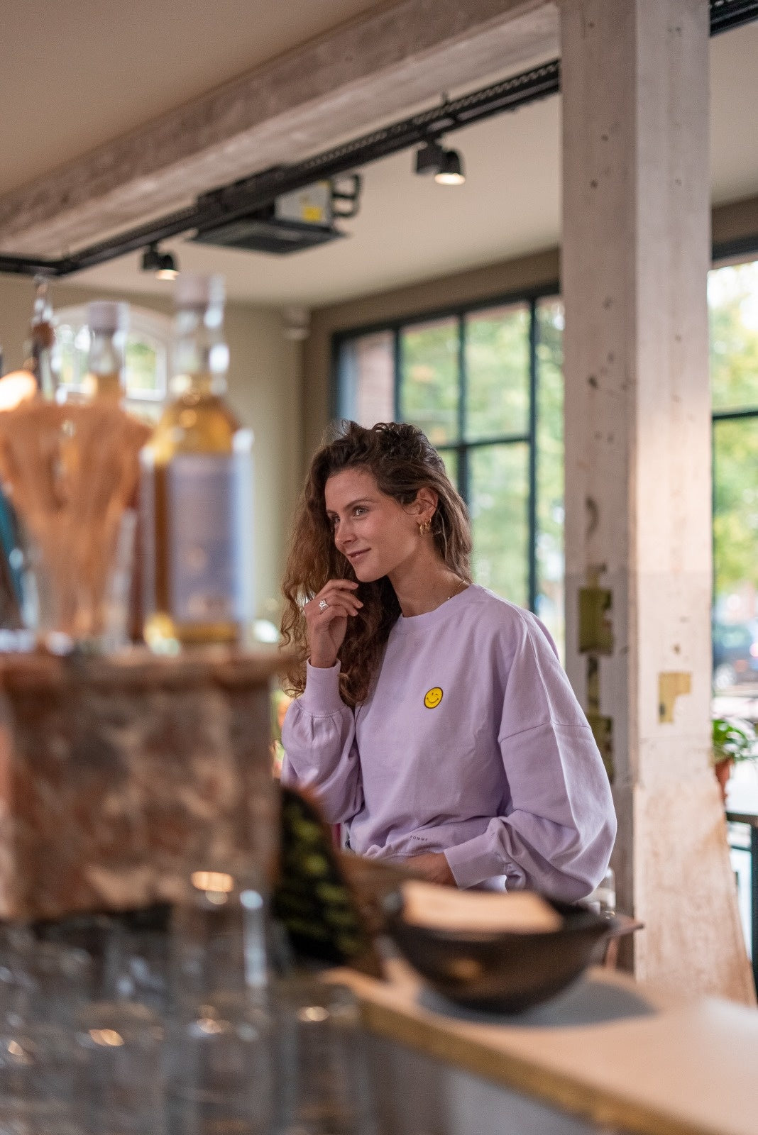 Vrouw in oversized lila trui met smiley gepersonaliseerd. 