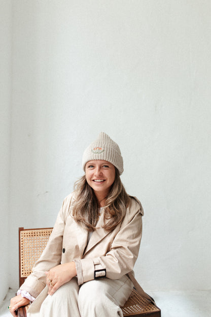 Vrouw met beige gebreide muts, trendy accessoire voor dames.