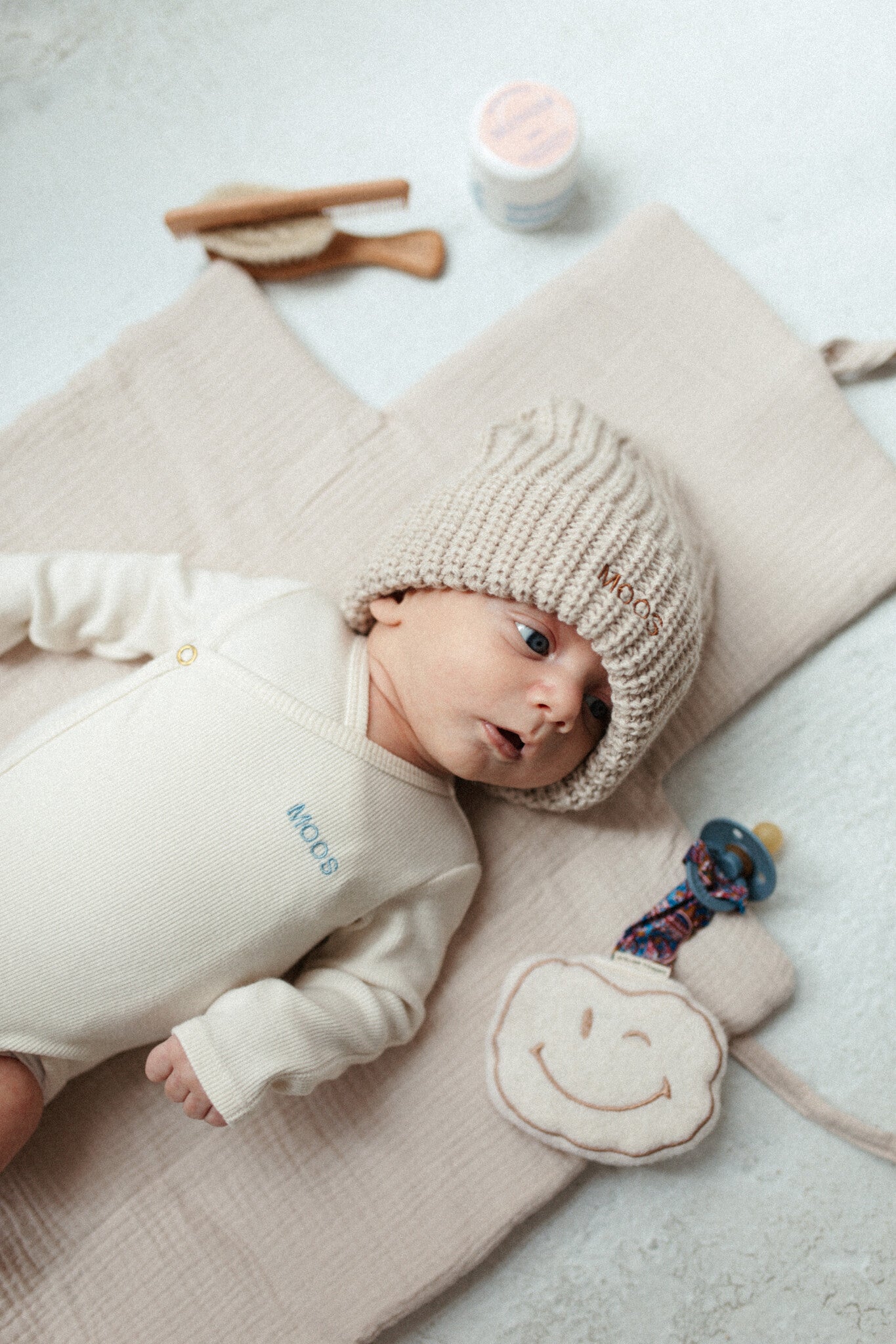 baby met een witte ronde speenkoord knuffel in het beige met wit