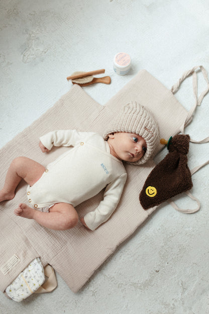 baby kijkend naar een speendoekje van bruine teddy stof met een smiley erop geborduurd