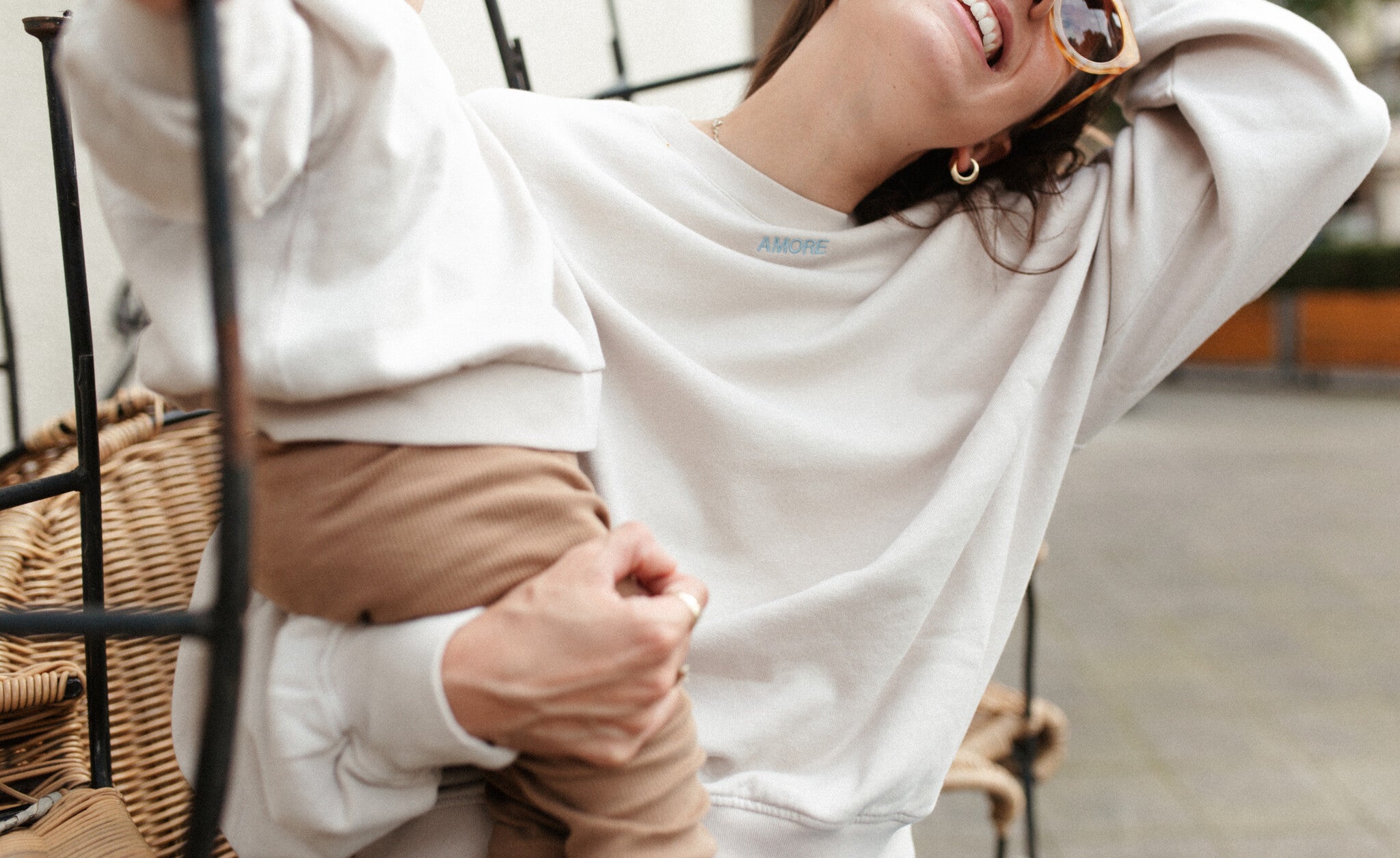 Moeder en vrouw in een oversized beige sweater. Gepersonaliseerd met amore in licht blauw. Gemaakt van 100% biologisch katoen.