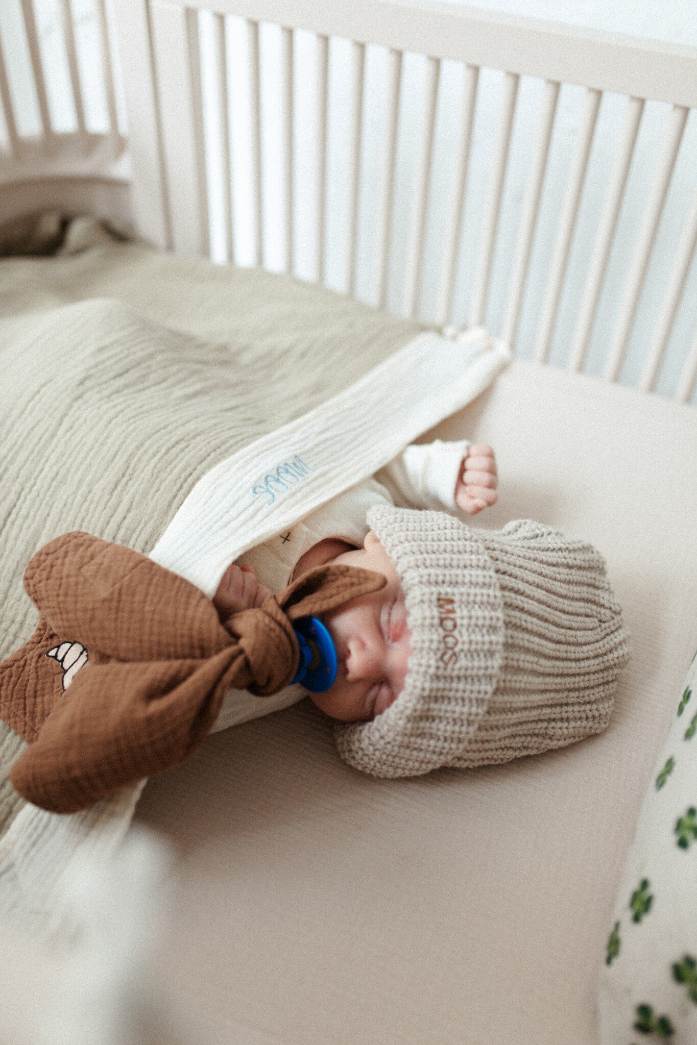 baby in bedje met een groen muslin deken met naam erop