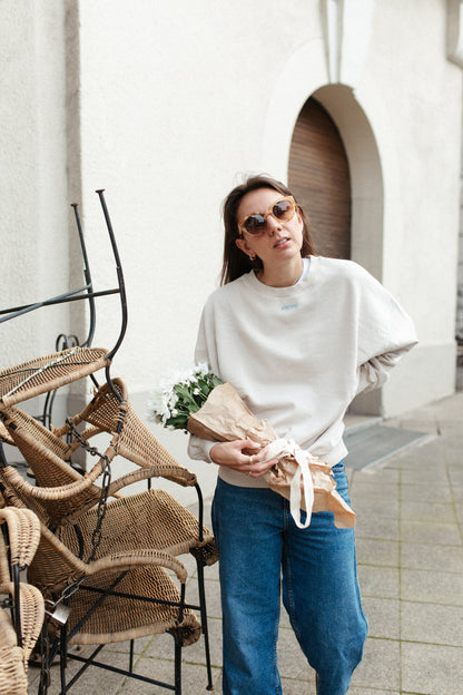 Moeder en vrouw in een oversized beige sweater. Gepersonaliseerd met amore in licht blauw. Gemaakt van 100% biologisch katoen.